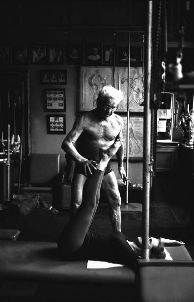 NEW YORK - OCTOBER 1961: Joe Pilates, Inventor, physical fitness guru and founder of the Pilates exercise method instructs a client on his mat and works her through an exercise routine in his 8th Avenue studio on October 4, 1961 in New York City, New York. (Photo by I.C. Rapoport/Getty Images)